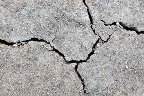 Aged concrete driveway surface showing extensive interconnected settlement cracking
