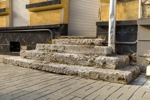 Poured concrete entry steps with a landing and handrail at a residential building
